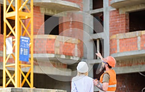 Woman engineer and builder communicate at construction site. Relationships between construction clients and participants