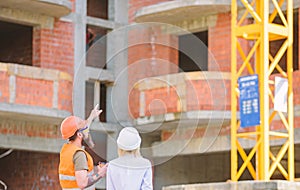 Woman engineer and builder communicate at construction site. Relationships between construction clients and participants