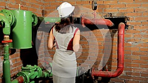 Woman engineer checking technical data of heating system equipment in a boiler room. Engineer working in temperature