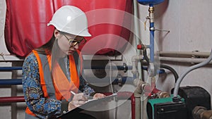 Woman engineer checks the meter readings in the boiler room.