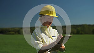 Woman engineer in a hard hat is writing notes while standing in the field