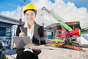 Woman engineer holding digital tablet wtih smile in construction site background