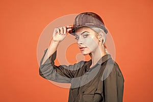 woman engineer in protective helmet and boilersuit on orange background, labouring