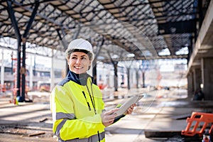 A woman engineer with tablet standing on construction site, working.