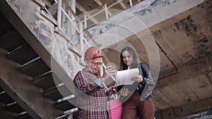 Woman engineer talking to a foreman on the construction site, solving organizational issues.