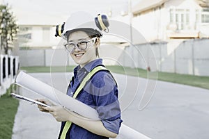 Woman Engineer wear safety glasses , hardhat and earmuff holding blueprint and check list smiling face. Concept of engineering