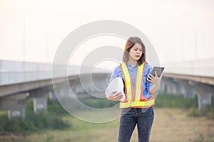 Woman Engineer With White Security Helmet holding tablet Standing On Construction Site