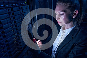 Woman engineer working in datacenter by server storage racks