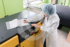 Woman engineer writing observations about equipment and producti photo