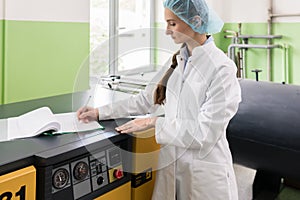 Woman engineer writing observations about equipment and production photo