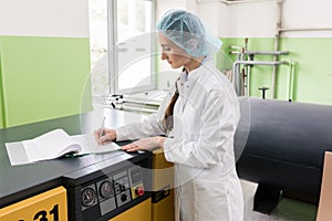 Woman engineer writing observations about equipment and production photo