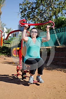 Woman enhancing her arms in fitness station