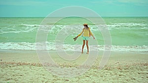 woman enjoing walking sandy beach at windy stormy day, waving sea. Getaway dream concept. Freedom summer girl enjoying