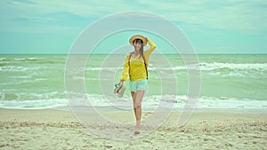 woman enjoing walking sandy beach at windy stormy day, waving sea. Getaway dream concept. Freedom summer girl enjoying