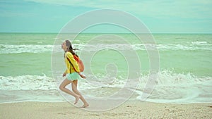 woman enjoing walking sandy beach at windy stormy day, waving sea. Getaway dream concept. Freedom summer girl enjoying