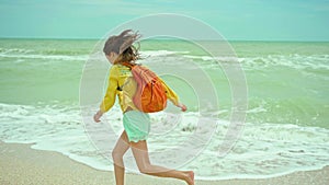 woman enjoing walking sandy beach at windy stormy day, waving sea. Getaway dream concept. Freedom summer girl enjoying