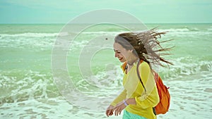 woman enjoing walking sandy beach at windy stormy day, waving sea. Getaway dream concept. Freedom summer girl enjoying