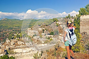 Woman enjoying amazing view of stone ruins of abandoned town Kayakoy in Turkey