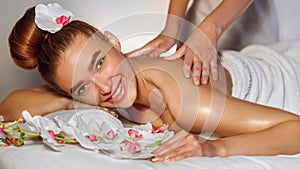 Woman enjoying back massage, smiling at camera