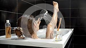 Woman enjoying a bath, with water cascading over her legs as she washes them under the shower