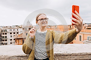 Woman enjoying beautiful day cityscape of Rome, taking selfie photo, while sitting on the top of famous Spanish steps