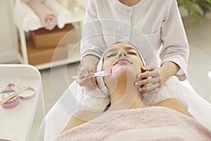 Woman enjoying clay mask while getting facial treatment in spa salon or beauty parlor