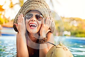 Woman enjoying a coconut alcoholic drink while at pool bar