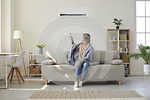 Woman enjoying cool fresh air in her living room with air conditioner on the wall photo