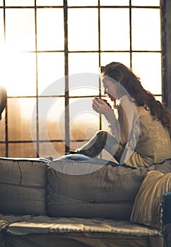 Woman enjoying cup of beverage in loft apartment