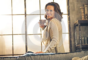 Woman enjoying cup of coffee in loft apartment