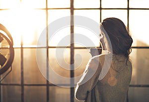 Woman enjoying cup of coffee in loft apartment