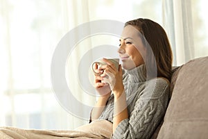 Woman enjoying a cup of coffee in winter at home