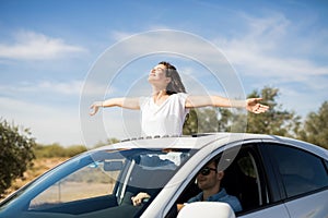 Woman enjoying the fresh air while boyfriend drive car