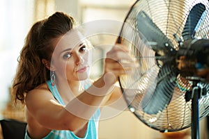 Woman enjoying fresh air in front of working fan