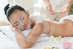 Woman enjoying getting a salt scrub beauty treatment at spa