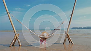 Woman enjoying hammock by the beach.