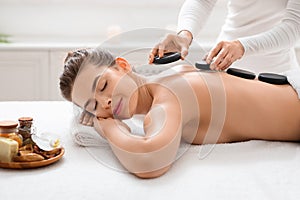 Woman enjoying her day at spa, receiving hot stones massage