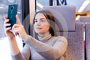 Woman enjoying journey in train, taking pictures on cellphone