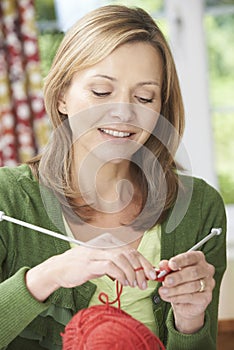 Woman Enjoying Knitting Garment At Home