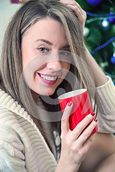 Woman enjoying a large cup of freshly brewed hot tea as she relaxes on a sofa in the living room. Morning coffee. Woman holds a r