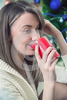 Woman enjoying a large cup of freshly brewed hot tea as she relaxes on a sofa in the living room. Morning coffee.