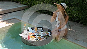 Woman enjoying luxurious breakfast by poolside