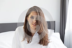 Woman enjoying morning awakening in a soft snow-white bed