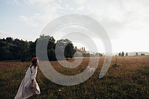 Woman enjoying nature and walking with golden labradore in meadow. Outstretched arms fresh morning air summer Field at