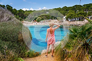 A woman enjoying a peaceful moment on a cliff, overlooking Cala Gat beach in Mallorca