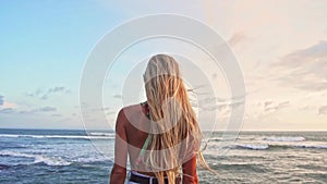 Woman enjoying sea blonde hair blowing in wind Travel Lifestyle vacations and harmony with nature relaxing concept rear