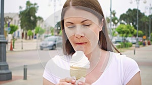 Woman enjoying soft ice cream cone outdoors. Female traveler eating frozen yogurt on street alone