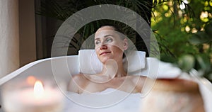 woman enjoying spa bath with foam and scented candles. body care, aromatherapy and mental wellness