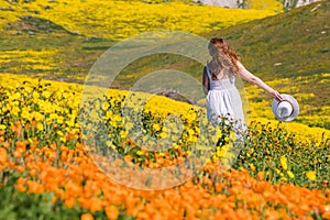 Woman enjoying spring among beautiful meadow full of bright yellow and orange wild flowers