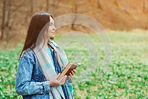 Woman enjoying spring day at nature. Lifestyle, people and spring time. Young woman with book on the walk